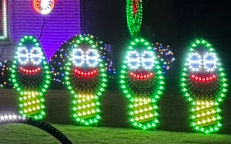 The four singing bulbs on the lawn, glowing green with white eyes and red smiles. From left to right: Elden, Felix, Ralphie and Zuzu.